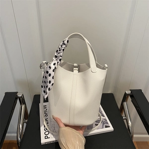 Minimalist white litchi leather bucket bag featuring a polka dot silk scarf on handle