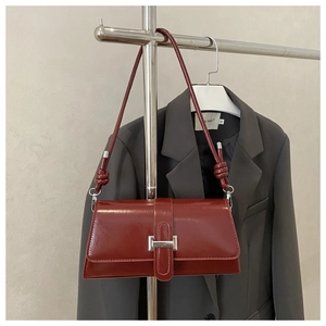 Macro detail of wine red baguette bag with glossy texture and silver metal buckle