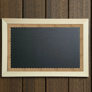 Krijtbord met golvende jute rand en licht houten frame op donkere houten vloer