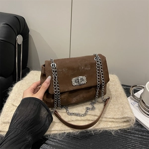 Brown suede chain shoulder bag with rhinestone swivel lock on soft knit background