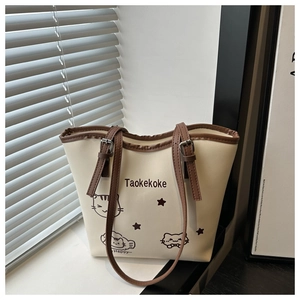 Detail of beige tote bag featuring cartoon cat prints and adjustable brown strap