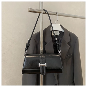 Detail showing sleek black shoulder bag with silver buckle and stylish knotted strap design