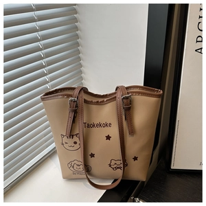 Close-up of beige tote bag with cat print, star patterns and brown adjustable straps