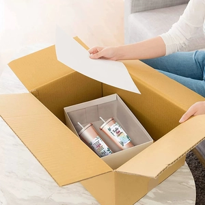 Auspacken von zwei Roségold-Edelstahlbechern mit Pflegekarten im Versandkarton