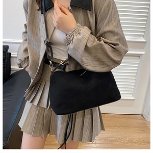 Chic black matte crossbody bag paired with a striped blazer for a stylish commuter look