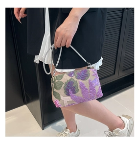 Detail of floral embroidery and purple sequins on an elegant shoulder bag with silver chain