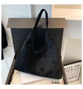 Detail of laser-cut floral pattern on black suede tote bag with minimalist aesthetic