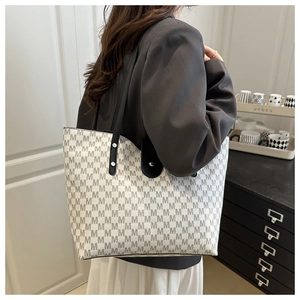 Detail of a large tote bag with M letter print and black leather shoulder straps