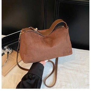 Detail of brown suede crossbody bag showing soft texture and gold-tone zipper hardware