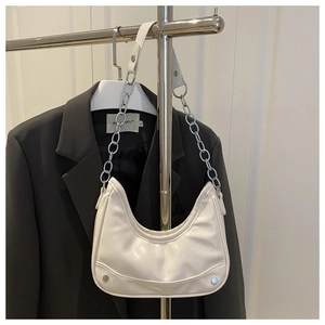 White crescent underarm bag featuring silver chain strap and metal stud details