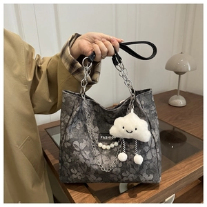 Détail du sac cabas en toile à fleurs avec chaîne en perles et charme nuage en peluche
