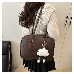 Detail view of retro brown leather bowling bag with cute white cloud plush pendant accessory