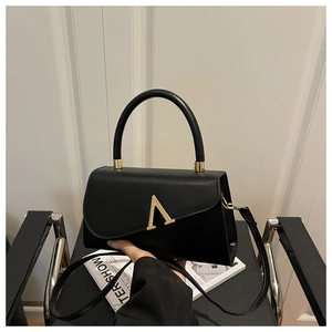 Detail der schwarzen Kunstledertasche mit goldener V-Schnalle und rundem Griff
