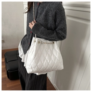 Close-up of white quilted bucket bag with golden chain and soft leather texture detail