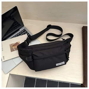 Gros plan d'un sac de poitrine en nylon noir avec sangle réglable et logo sur bois