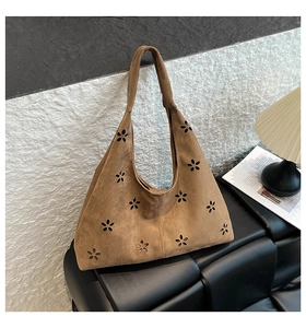 Detailed laser-cut petal pattern on a brown suede tote bag in a cozy indoor setting