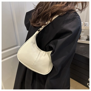 Detail of a creamy white crescent hobo bag featuring fine stitching and gold buckle