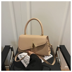 Detail der beigen PU-Lederhandtasche mit goldener V-Schließe und rundem Haltegriff