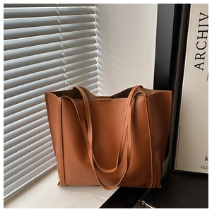 Close-up of brown PU tote bag showing matte texture and fine side stitching detail