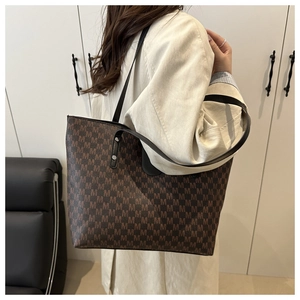 Detailed side view of large tote bag with M-pattern print and black leather straps