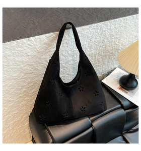 Detail view of black suede hobo bag featuring laser-cut floral patterns and premium texture