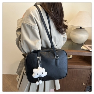 Chic black bowling bag with white cloud plush charm shown on a female shoulder