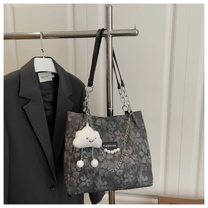 Detalle de bolso tote con flores, correa de cadena y un colgante de nube blanca