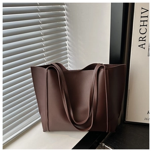 Detail of dark brown matte leather tote bag with dual shoulder straps in natural lighting