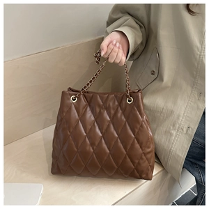Close-up of brown quilted tote bag with diamond stitching and gold chain strap detail