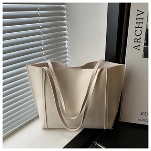 Minimalist cream-colored PU leather tote bag with slender straps in soft natural sunlight