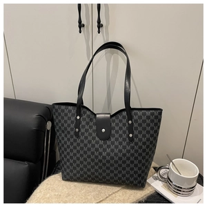 Close-up of the black monogram tote bag showing metal buckle detail and rivets
