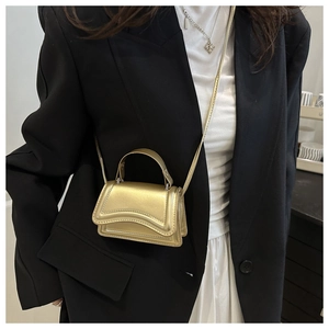Détail du mini sac doré métallisé avec rabat ondulé et fine bandoulière réglable
