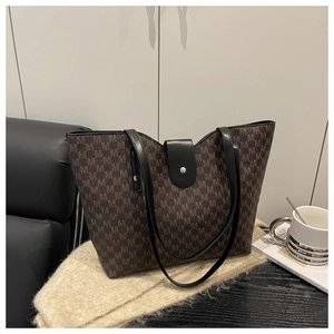 Macro detail of brown monogram tote bag with black leather trim and silver hardware