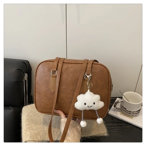 Detail of vintage brown PU leather tote with a cute white cloud plush charm accessory