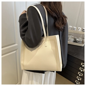 Detail view of large beige tote bag with pebbled texture shown on a female model