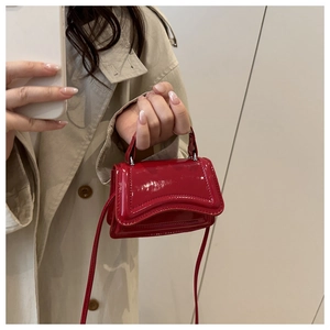 Selfie miroir montrant un mini sac à main en cuir verni rouge avec finition brillante