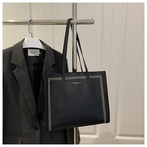 Detail of black leather tote bag with gold stud trim and elegant fashion lettering