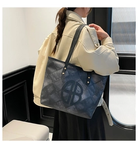 Detail of grey gradient checkered tote bag with circular logo and leather straps