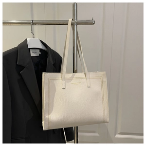 Close-up of cream white lychee leather tote bag with decorative stitching and long straps