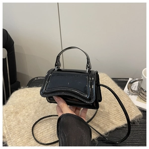 Vue détaillée du mini sac à main en cuir verni noir avec finition brillante et poignée