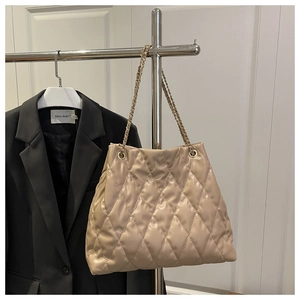Detail of beige quilted tote bag with gold chain strap and soft PU leather texture