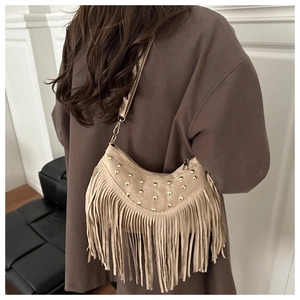 Dettaglio borsa a mezzaluna beige con borchie dorate e lunghe frange stile bohémien