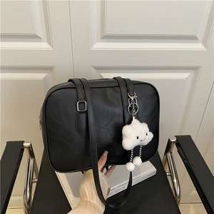 Chic black bowling tote bag with a cute white cloud charm for women on a chair