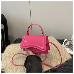 Vue détaillée du mini sac en cuir verni magenta avec rabat ondulé et poignée