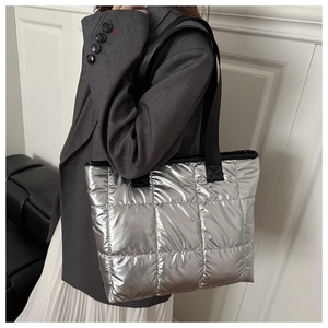Detail der silbernen Stepptasche mit Metallic-Finish und breitem schwarzem Gurt