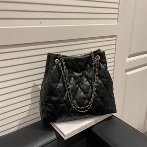 Chic black quilted tote bag with gold chain strap on a minimalist display background