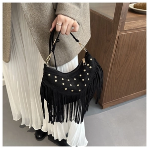 Dettaglio di borsa a mezzaluna in camoscio nero con borchie dorate e lunghe nappe boho