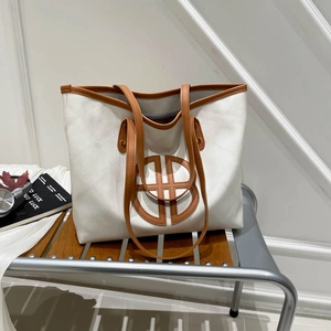Large capacity vintage tote bag in cream and brown leather on a modern metal bench