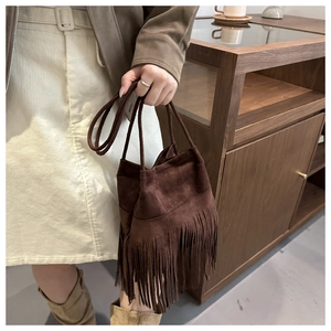 Détail du sac seau en daim marron foncé avec de longues franges et cordon de serrage