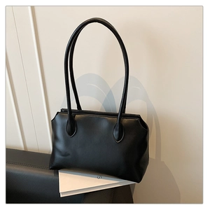 Detailed side view of black minimalist tote bag with smooth matte finish and pleat details